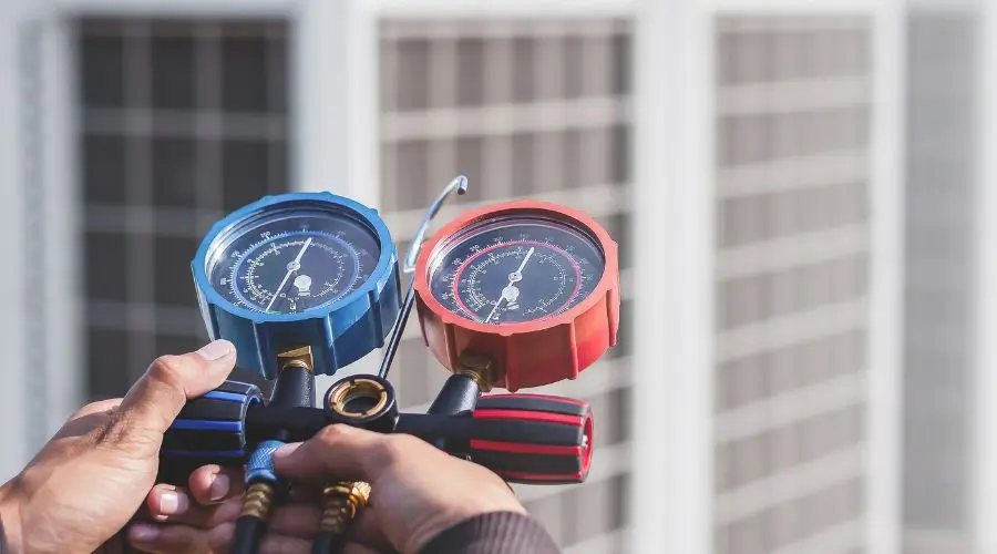 Man holding refrigerant gauges for air conditioning maintenance and repair, emphasizing HVAC service expertise.