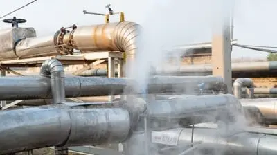 Industrial piping system with steam visible, indicating a possible leak or release of pressure in Hemet, California.