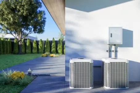 Air conditioning units positioned outside a home, showcasing a modern HVAC system in a landscaped yard, relevant to air conditioning maintenance and refrigerant issues.