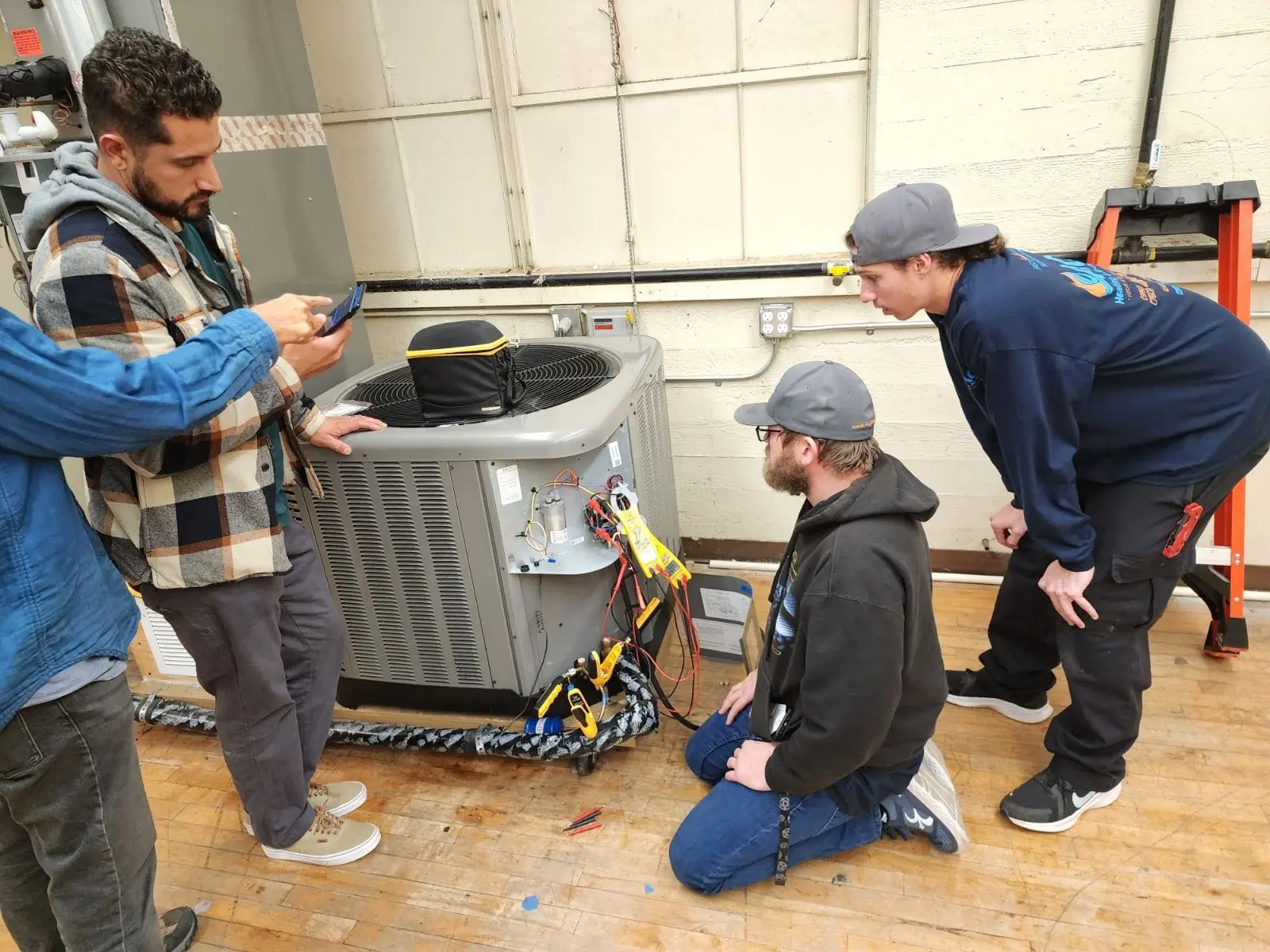 Technicians inspecting an air conditioning unit, discussing maintenance and repairs, in a professional HVAC setting.
