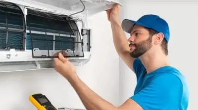 Technician performing maintenance on an air conditioning unit, emphasizing the importance of timely AC repair services for home comfort and efficiency.