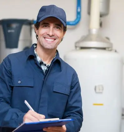 Smiling technician in blue uniform holding a clipboard, standing in front of a water heater in a utility room, ready for AC maintenance services in California.