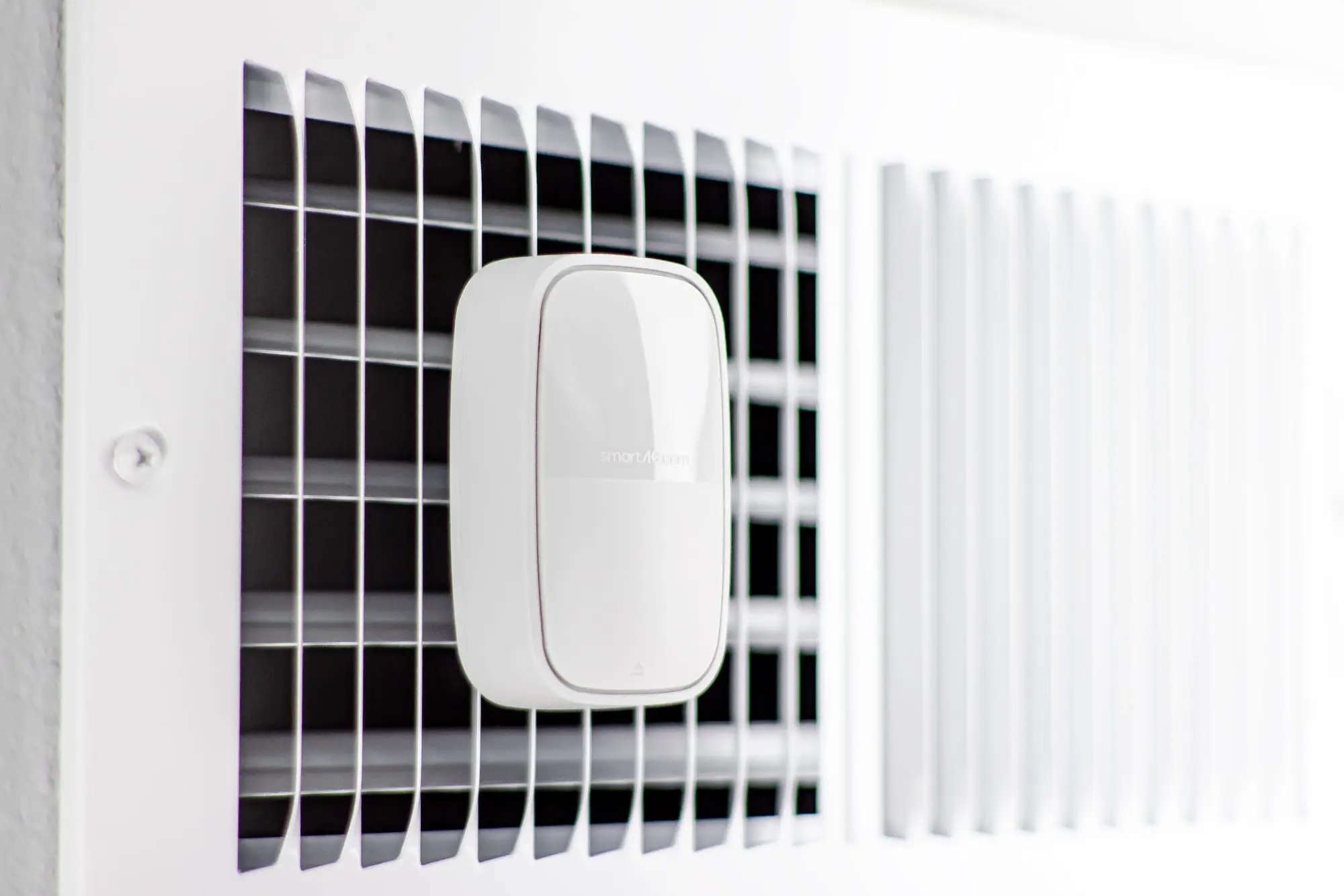 Smart AC sensor mounted on air conditioning vent, emphasizing modern HVAC technology for efficient home climate control.