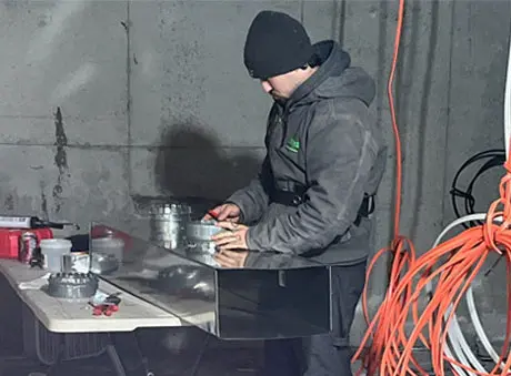 Worker at workstation in industrial setting, using tools and equipment for HVAC repairs at Clark's Home Services.