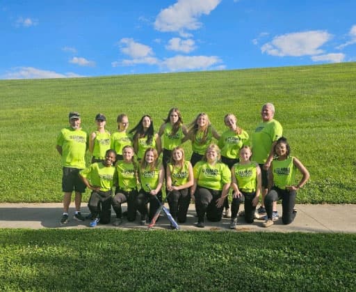 A youth softball team wearing neon green Clark's Home Services jerseys posing for a group photo outdoors with their coaches.