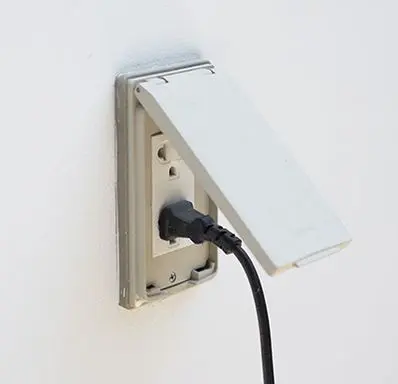 Outdoor electrical outlet with a protective cover and plugged-in device, relevant to home improvement and electrical safety in Charlotte, NC.