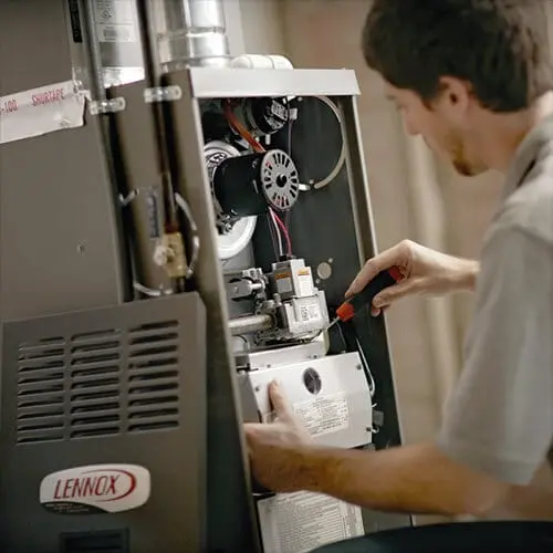 Technician repairing a Lennox furnace, showcasing internal components and tools at Acosta Heating, Cooling & Electrical.