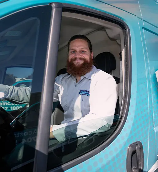 Smiling Acosta technician in uniform sitting in a branded service van, showcasing professional electrical services and customer care.