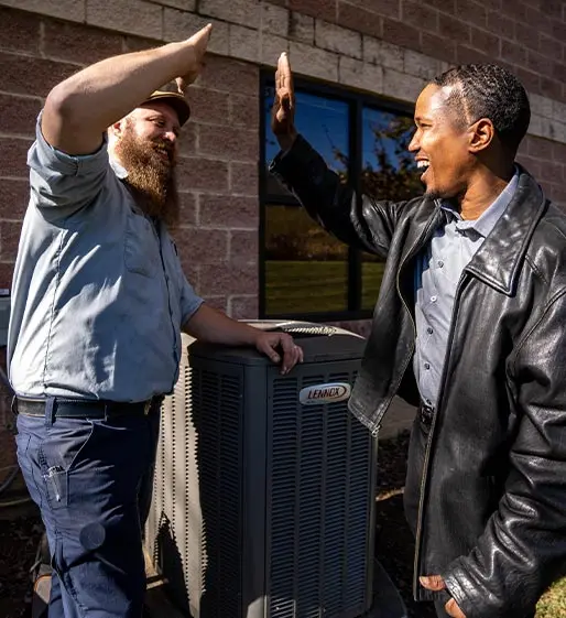 Electricians celebrating successful service, high-fiving near Lennox HVAC unit, emphasizing customer satisfaction and professional service at Acosta Heating, Cooling & Electrical.