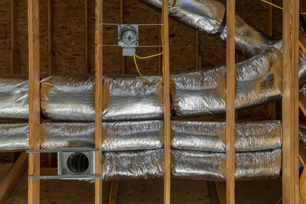 Ductwork installation in new construction, showcasing insulated silver ducts and framing, essential for HVAC air circulation and efficiency.
