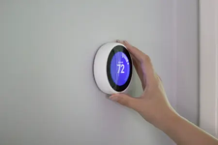 Smart thermostat being adjusted to 72 degrees Fahrenheit, highlighting energy efficiency and home comfort in HVAC systems.
