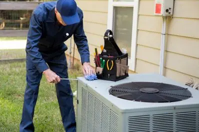 HVAC technician performing maintenance on an outdoor air conditioning unit.