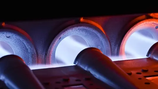 A properly functioning HVAC gas furnace burner assembly emitting steady blue flames during a routine safety inspection.