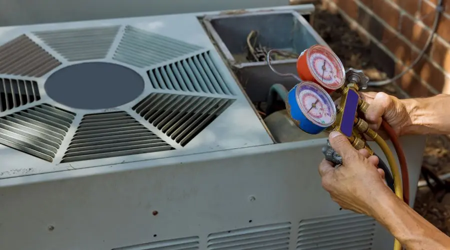 Hands holding pressure gauges connected to an air conditioning unit, demonstrating maintenance procedures essential for energy efficiency and reliability.