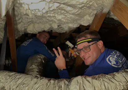 Technicians installing HVAC system in an attic, showcasing expertise in air conditioning services for License to Chill.