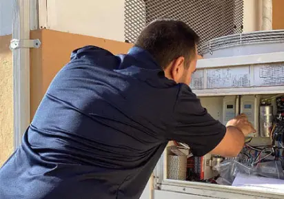 HVAC technician performing maintenance on an air conditioning unit, demonstrating professional AC repair services for optimal indoor comfort.