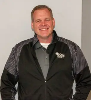 Jon, team member at SOS Heating & Cooling, smiling in company-branded jacket, showcasing expertise in HVAC services and community involvement.