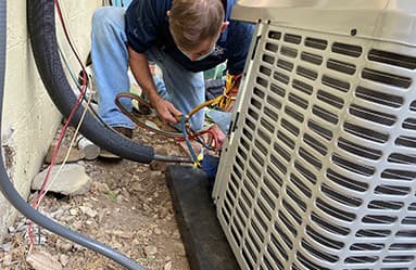 Technician performing maintenance on an outdoor air conditioning unit, ensuring optimal performance for energy efficiency and comfort.