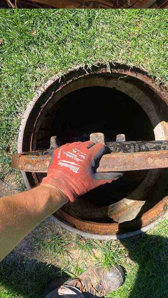 Sewer worker inspects grate
