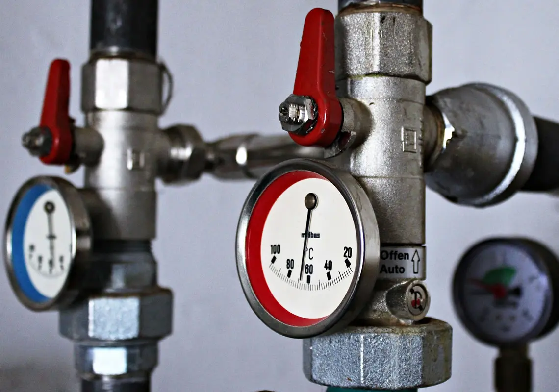 Pressure gauges and valves on a plumbing system, highlighting maintenance for heating systems in winter.