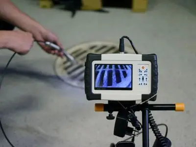 Plumber using a sewer inspection camera to diagnose toilet backup issues, showcasing professional plumbing techniques for identifying clogs and sewer line defects.