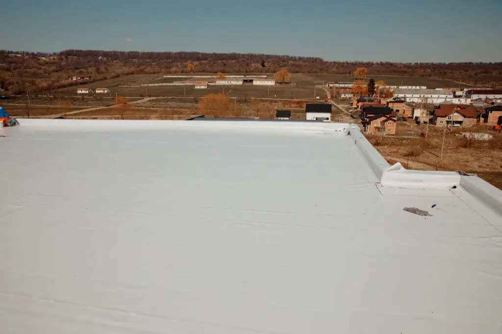 White commercial roof showing flat roof materials with membrane surface overlooking town