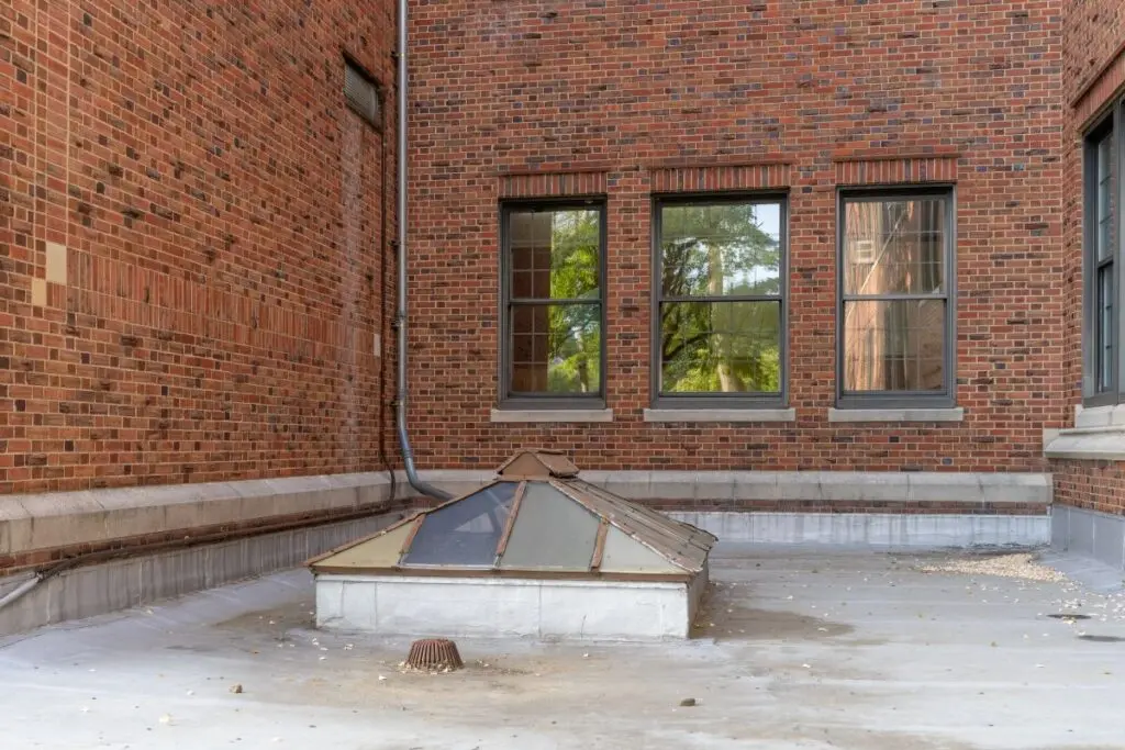 Old, vintage metal framed double pitched skylight on a flat commercial, industrial, or school rooftop