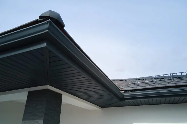 House corner with brown metal planks siding and roof with steel gutter rain system. Roofing, construction, drainage pipes installation.