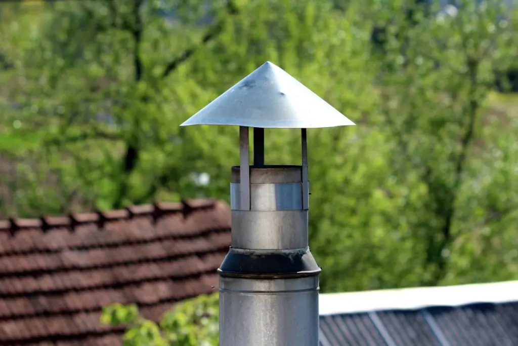 A modern stainless steel chimney flue, topped with a conical cap to prevent rain ingress