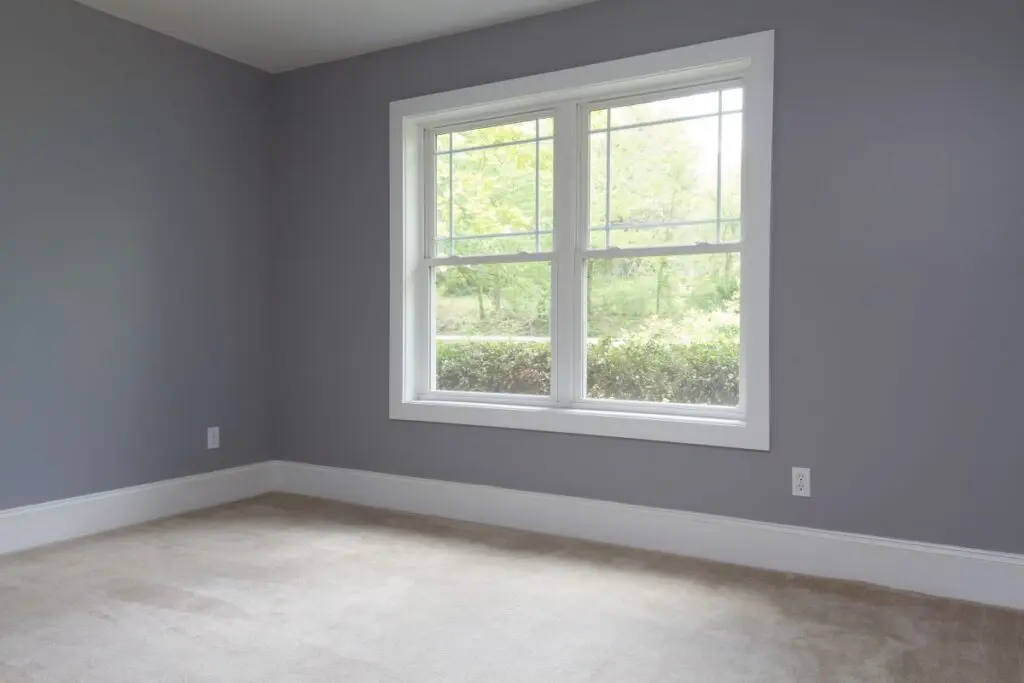 grey room with a big white window facing the woods