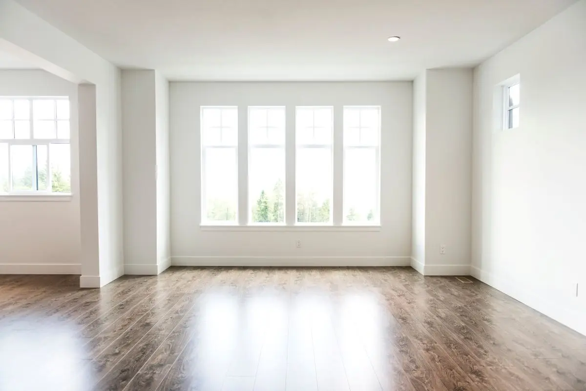 bright living room with wooden floors and large white windows