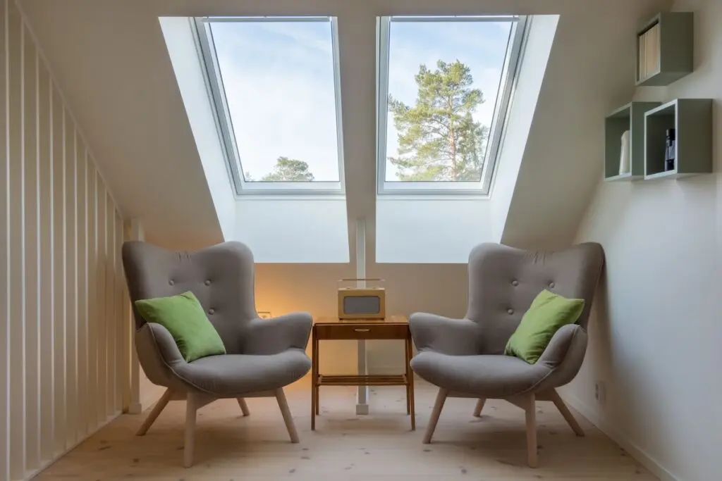 Two chairs sitting under a skylight in a sitting area
