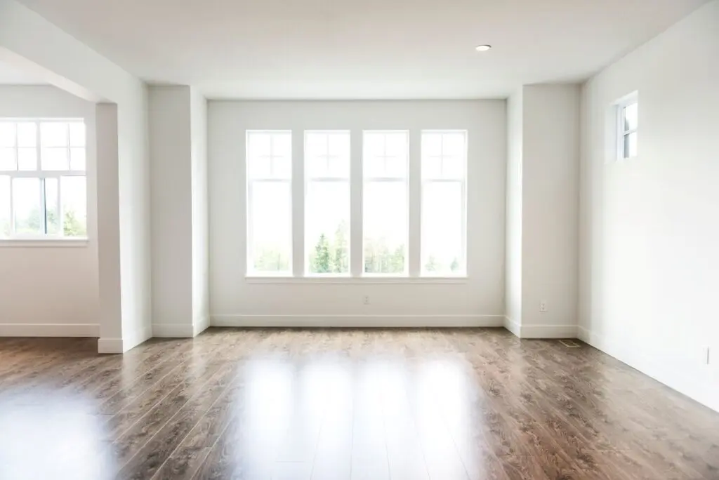 bright living room with wooden floors and large white windows