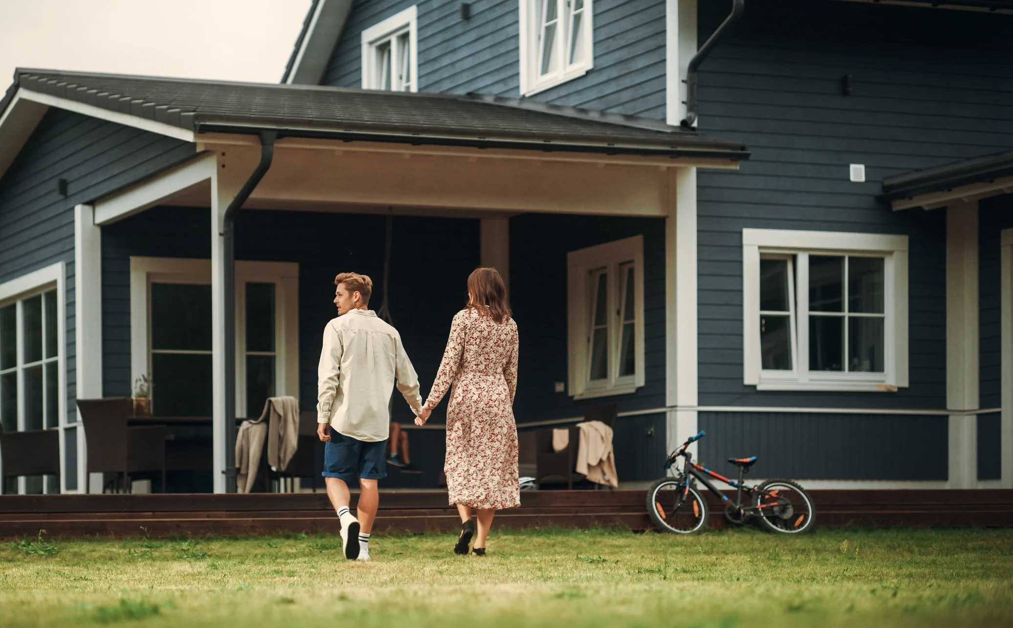 Happy young couple with kids outside gray home with new roof