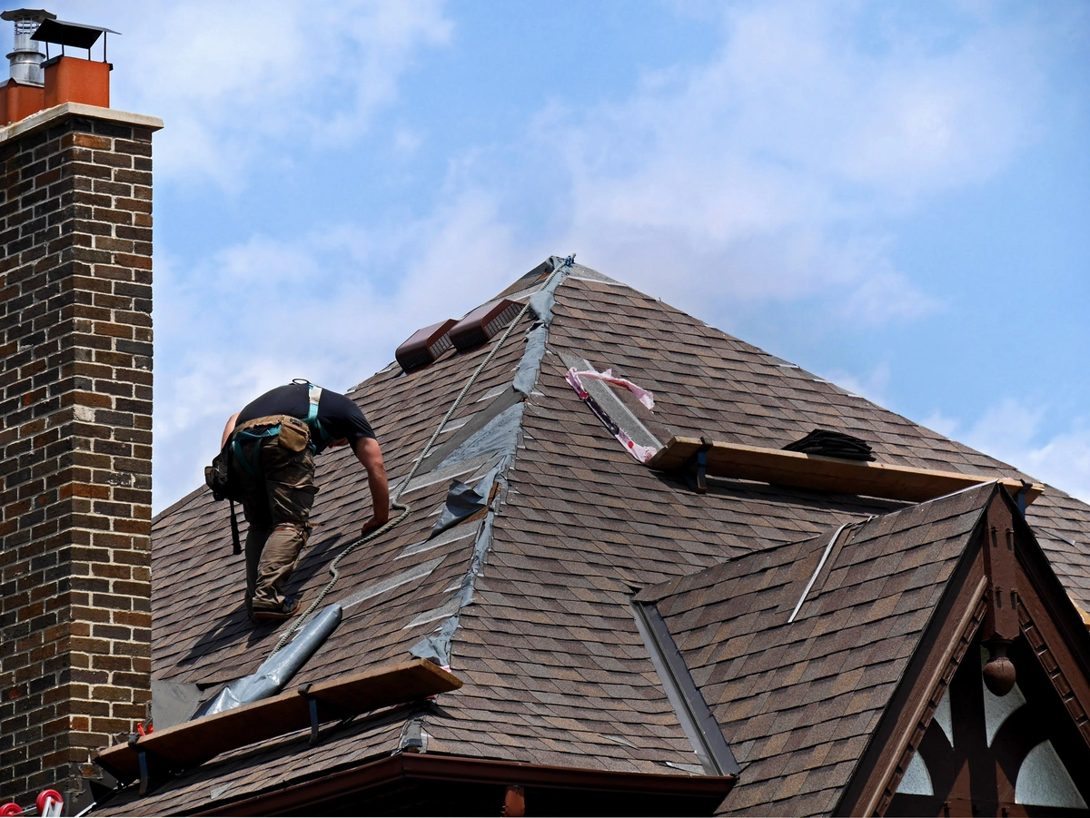 contractor performing a roof replacement on an older home