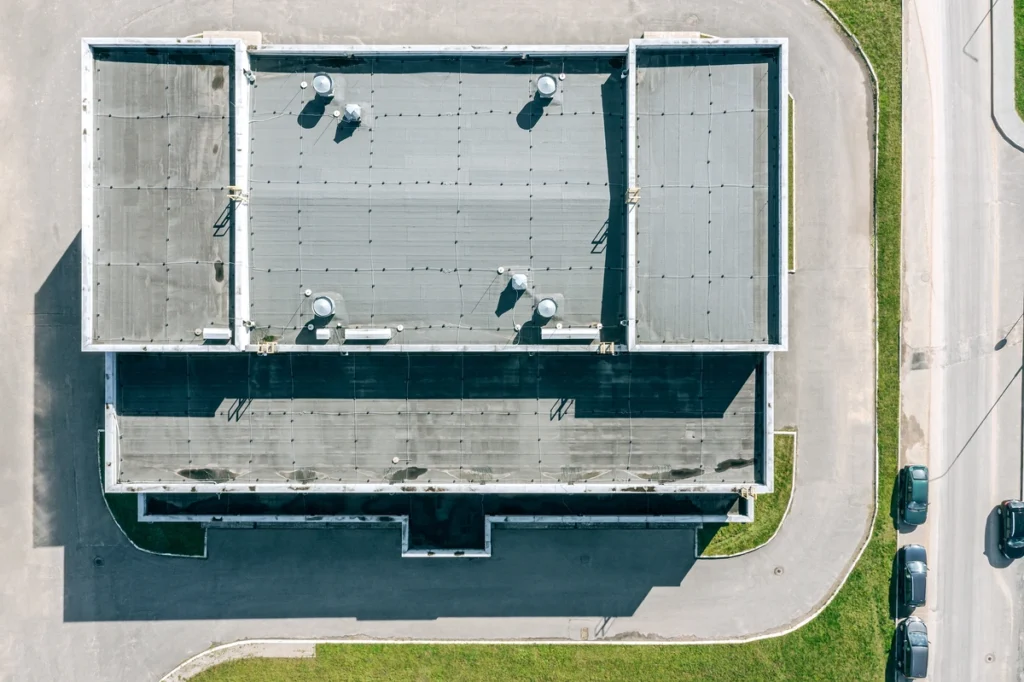 Aerial view of commercial building showing flat roof materials with membrane surface and vents
