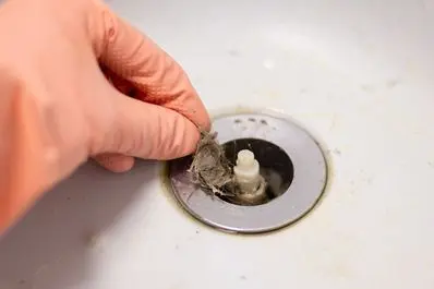 Man removes hair and debris from sink