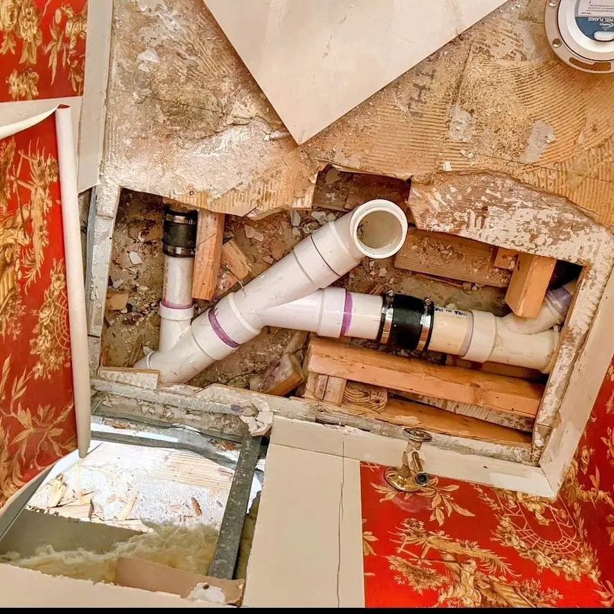New PVC drain line installed beneath a raised floor during a drain replacement