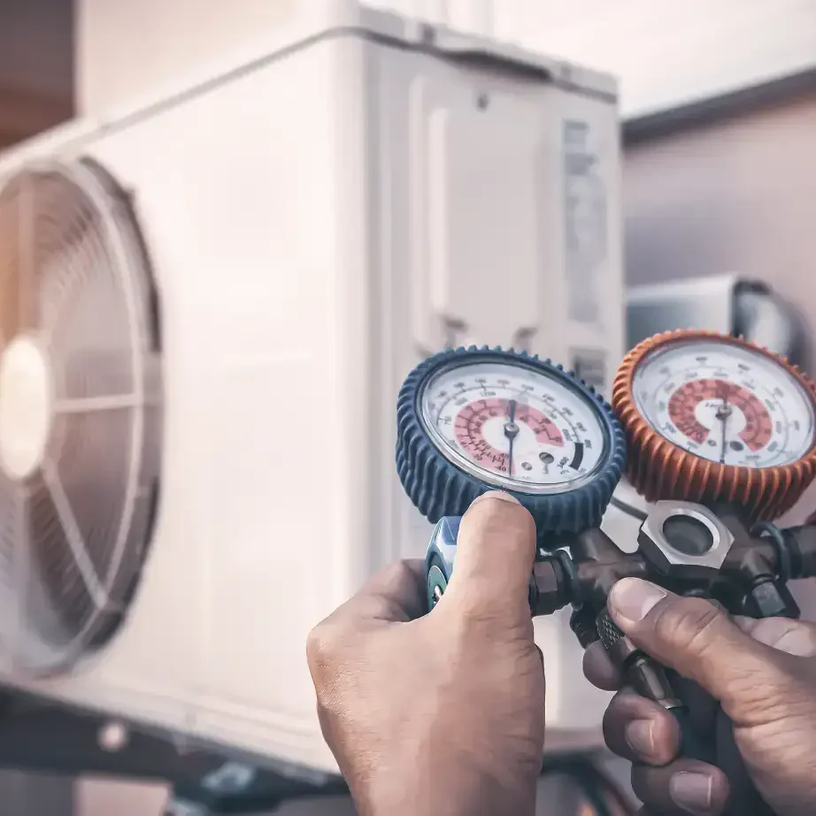 Technician checking refrigerant pressure on a heat pump outdoor unit in Bradenton & Sarasota, FL