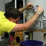 Person repairing a water heater with plumbing tools in an organized workspace, highlighting home maintenance efforts.