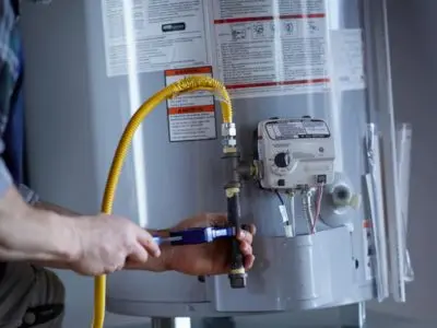 Plumber inspecting water heater connections and gas line for maintenance and repair services.