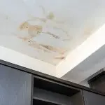 Ceiling with water damage stains and wooden cabinetry below, indicating plumbing issues needing a plumbing service.