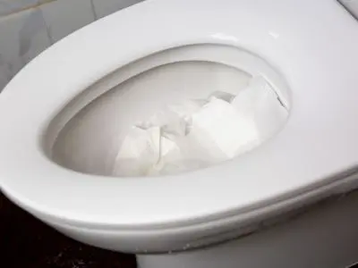 Toilet bowl filled with crumpled paper, illustrating common plumbing mistake of flushing inappropriate items instead of toilet paper.