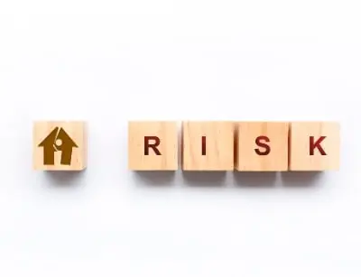 Wooden blocks spelling "RISK" with a house icon, symbolizing plumbing risks in commercial buildings.