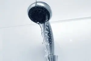 Showerhead leaking water, illustrating common bathroom plumbing issues such as dripping faucets and the need for maintenance.