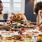 Couple enjoying a festive meal with turkey, side dishes, and wine at a beautifully arranged table.
