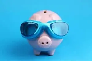 Piggy bank wearing blue swimming goggles, symbolizing savings and water conservation related to plumbing issues.