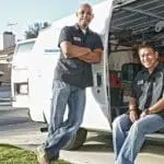 Two uniformed workers beside a service van with tools, showcasing a professional business environment.
