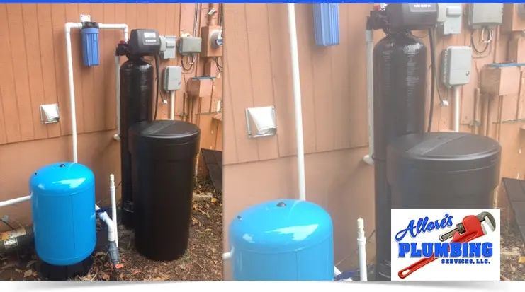 Water softening system installation featuring a black water softener tank, blue pressure tank, and plumbing connections, with Allore's Plumbing Services logo in the corner.