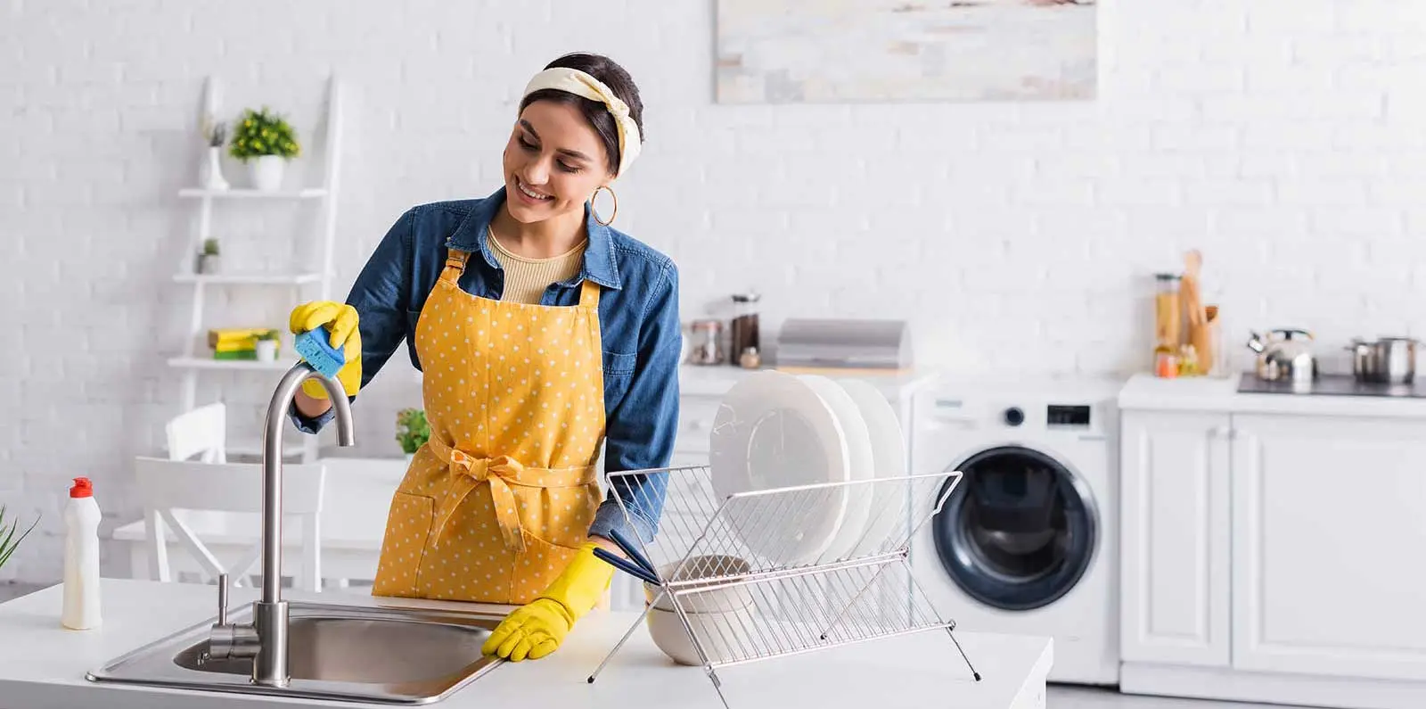 Woman cleaning a kitchen sink with supplies; related to Allore's Plumbing Services LLC.